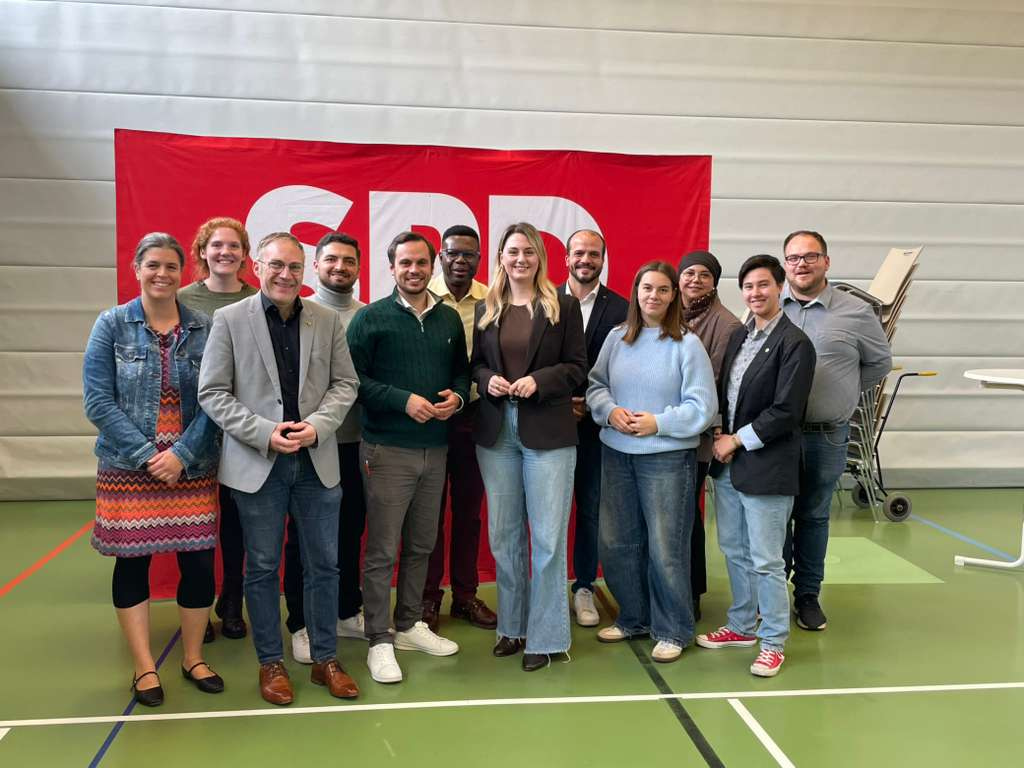 Gruppe von SPD-Mitgliedern steht für ein Foto vor einem roten Hintergrund, darunter der neu gewählte Co-Kreisvorsitzende Pascal Wasow.